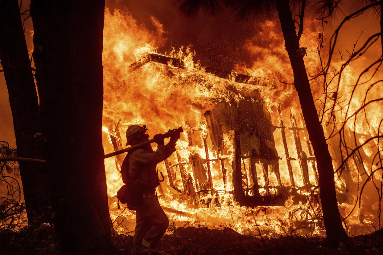 Firefighter Jose Corona sprays water as flames from the Camp Fire consume a home in Magalia, Calif., on Nov. 9, 2018. (Photo: Noah Berger/AP)