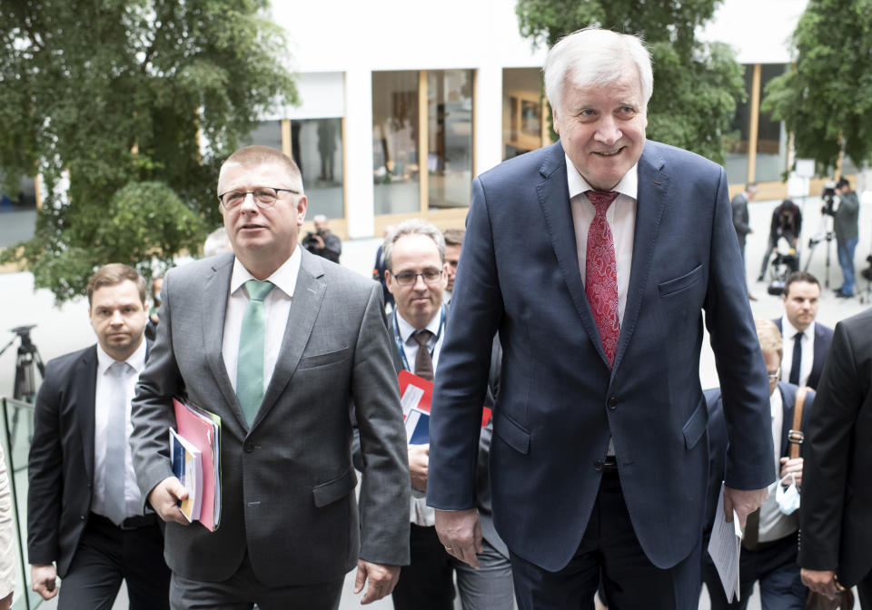 Horst Seehofer (CSU), Federal Minister of the Interior, Homeland and Construction, and Thomas Haldenwang, President of the Federal Office for the Protection of the Constitution (BfV), from right, come to the presentation of the 2019 Report on the Protection of the Constitution at the Federal Press Conference. (Bernd von Jutrczenka/dpa via AP)