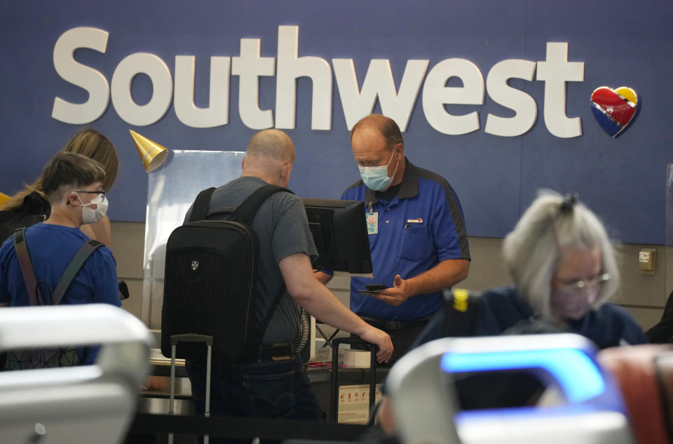 FILE - In this Wednesday, June 16, 2021, file photo, a Southwest Airlines ticketing agent helps a traveller at the check-in counter at Denver International Airport in Denver. Southwest Airlines plans to raise minimum pay to $15 an hour for about 7,000 employees, citing the need to attract and keep workers as the airline industry continues to recover from the pandemic. Southwest said Friday, June 25, that it intends for the raises to take effect on Aug. 1. (AP Photo/David Zalubowski, File)