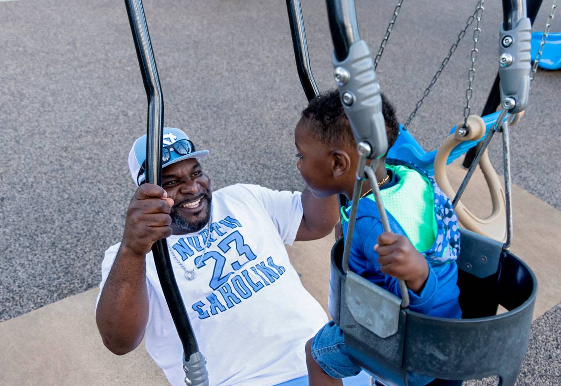 Atari Thomas smiles as he swings his youngest son, Bryson, at Barwell Road Park in Raleigh.