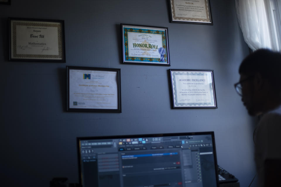 An Honor Roll certificate hangs on the bedroom wall of Bawi UK, 22, at his home in Providence, R.I., Saturday, Sept. 26, 2020. UK was a small child when his parents fled Myanmar, leaving him and his siblings to be cared for by their maternal grandmother. UK said the family suffered discrimination as Christians in a predominantly Buddhist nation. The military government was also trying to forcibly conscript his father. "To run for office, you had to be a Buddhist; to rent a house, you had to be Buddhist," said UK, a social work student at Rhode Island College and a youth leader at the Refugee Dream Center, an advocacy organization in Providence. (AP Photo/David Goldman)