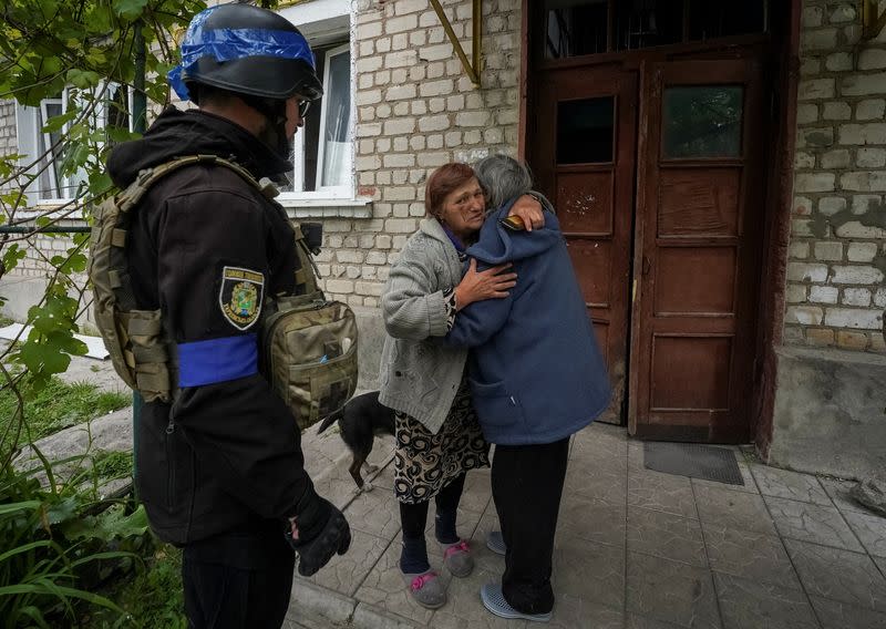A police officer helps a local resident during an evacuation to Kharkiv due to Russian shelling in the town of Vovchansk
