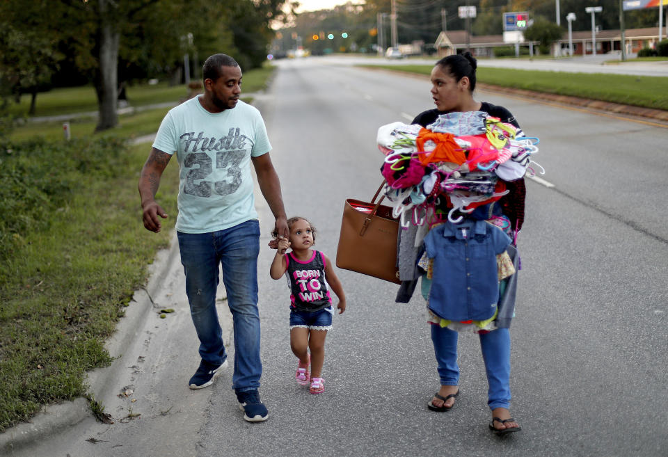 Jose Perez-Santiago, left, and Rosemary Acevedo-Gonzalez, walk with their daughter Jordalis, 2, after retrieving her clothing upon returning to their home for the first time since it was flooded in the aftermath of Hurricane Florence in Spring Lake, N.C., Wednesday, Sept. 19, 2018. "I didn't realize we would lose everything," said Perez-Santiago. "We'll just have to start from the bottom again." (AP Photo/David Goldman)