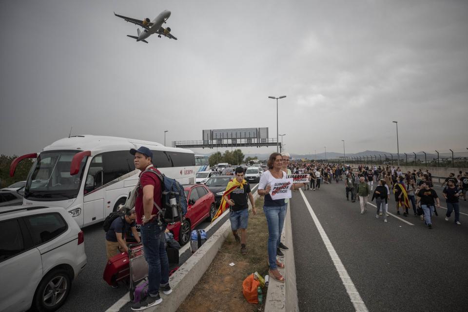 Protesters block the roads leading to El Prat airport, outskirts of Barcelona, Spain, Monday, Oct. 14, 2019. Spain's Supreme Court on Monday sentenced 12 prominent former Catalan politicians and activists to lengthly prison terms for their roles in a 2017 bid to gain Catalonia's independence, sparking protests across the wealthy Spanish region. The banners in the center read in Catalan "Freedom Political Prisoners" (AP Photo/Bernat Armangue)