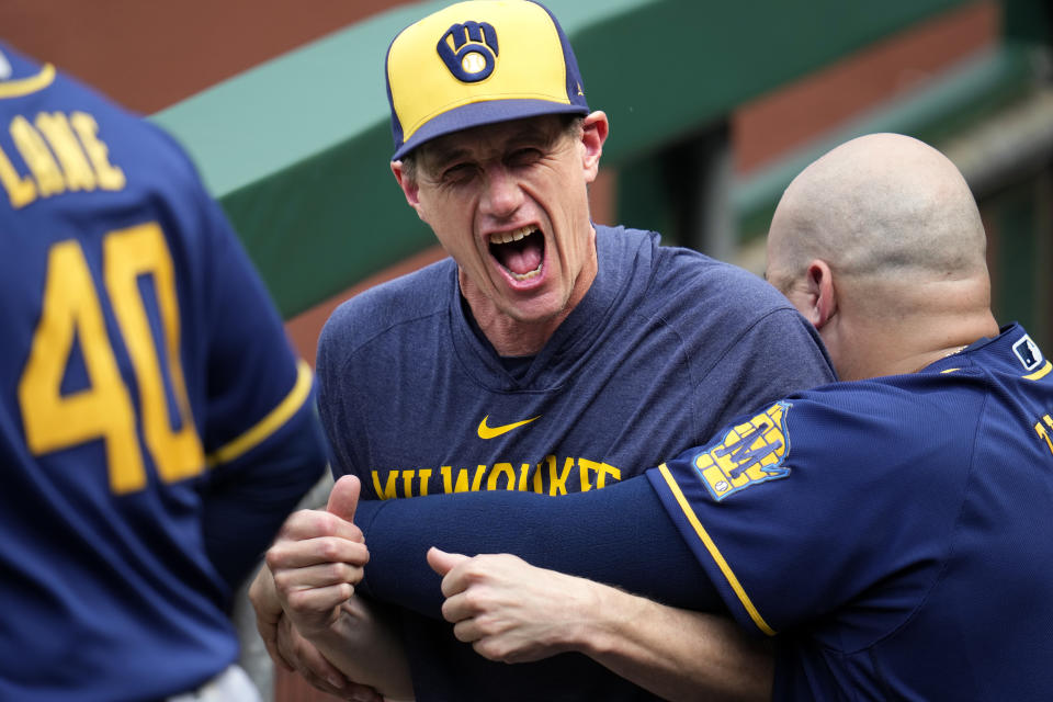 Milwaukee Brewers manager Craig Counsell, center, gets a playful bear hug from Rowdy Tellez in the dugout before the team's baseball game against the Pittsburgh Pirates in Pittsburgh, Saturday, July 1, 2023. (AP Photo/Gene J. Puskar)