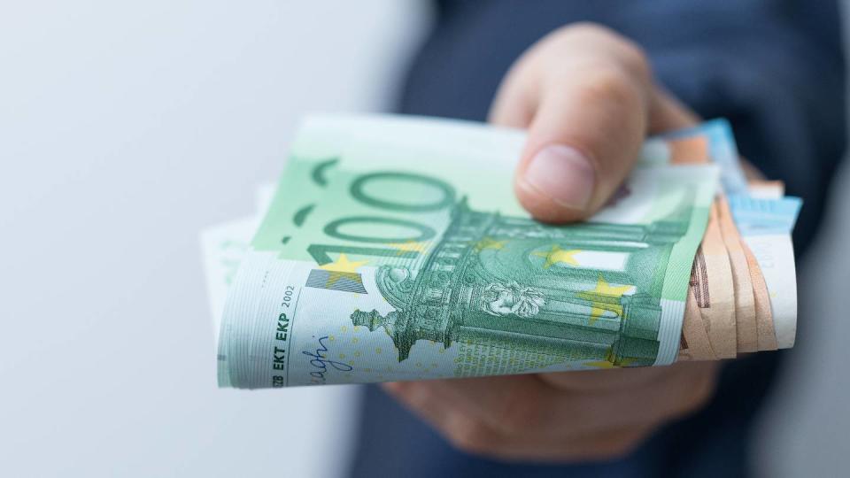 Un homme tient une liasse de billets en euros