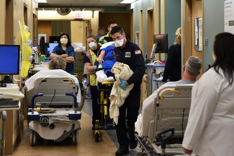 A Lansing ambulance crew weaves a gurney past occupied beds in the hallway in Sparrow’s emergency center.