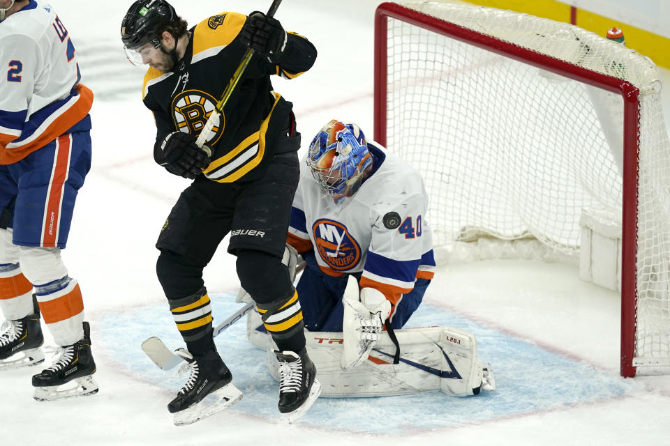 Boston Bruins left wing Jake DeBrusk (74) jumps to allow room for the puck which flies wide of New York Islanders goaltender Semyon Varlamov (40) in the first period of an NHL hockey game, Monday, May 10, 2021, in Boston. (AP Photo/Elise Amendola)