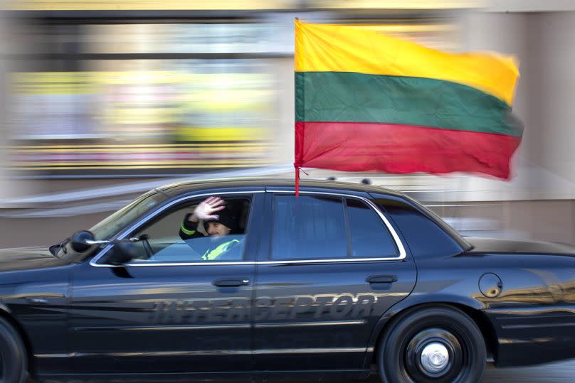 Ketvirtadienį, 2021 m. kovo 11 d., Vilniuje minint Nepriklausomybės atkūrimo dieną Gedimino gatve važiuoja automobilis su Lietuvos valstybine vėliava.