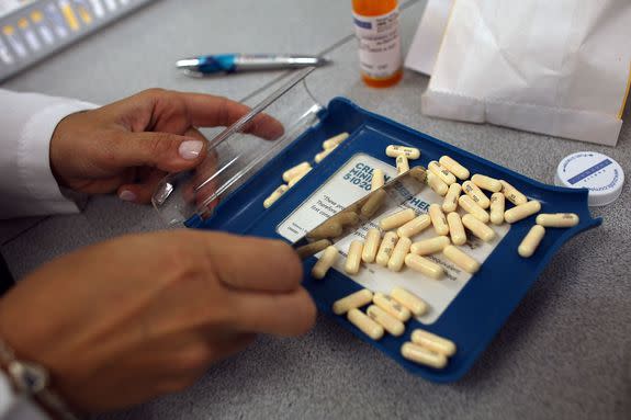 A pharmacy manager in Miami counts out the correct number of antibiotic pills to fill a prescription.