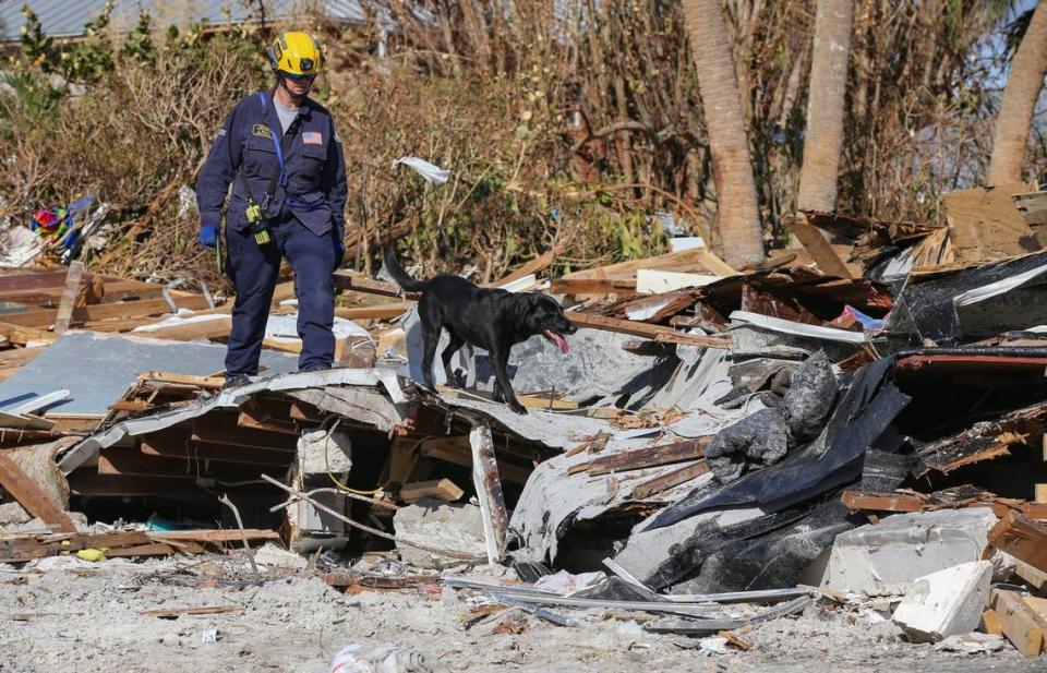 El miembro del Grupo de Trabajo de Búsqueda y Rescate Urbano de la Florida, J. Brown, busca en una casa dañada con el perro de búsqueda y recuperación Phame en Fort Myers Beach, el lunes 3 de octubre de 2022.