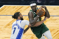 Milwaukee Bucks guard Jrue Holiday, right, tries to get by Orlando Magic guard Michael Carter-Williams (7) on his way to the basket during the first half of an NBA basketball game, Sunday, April 11, 2021, in Orlando, Fla. (AP Photo/John Raoux)