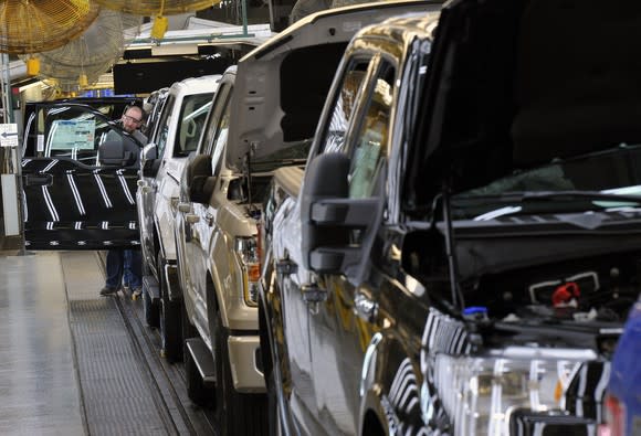 A line of mostly-assembled F-150 pickups moving down an assembly line.