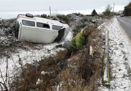 A farmer inspects a taxi after it crashed onto his land in icy conditions near Coalville in Britain January 13, 2017. REUTERS/Darren Staples