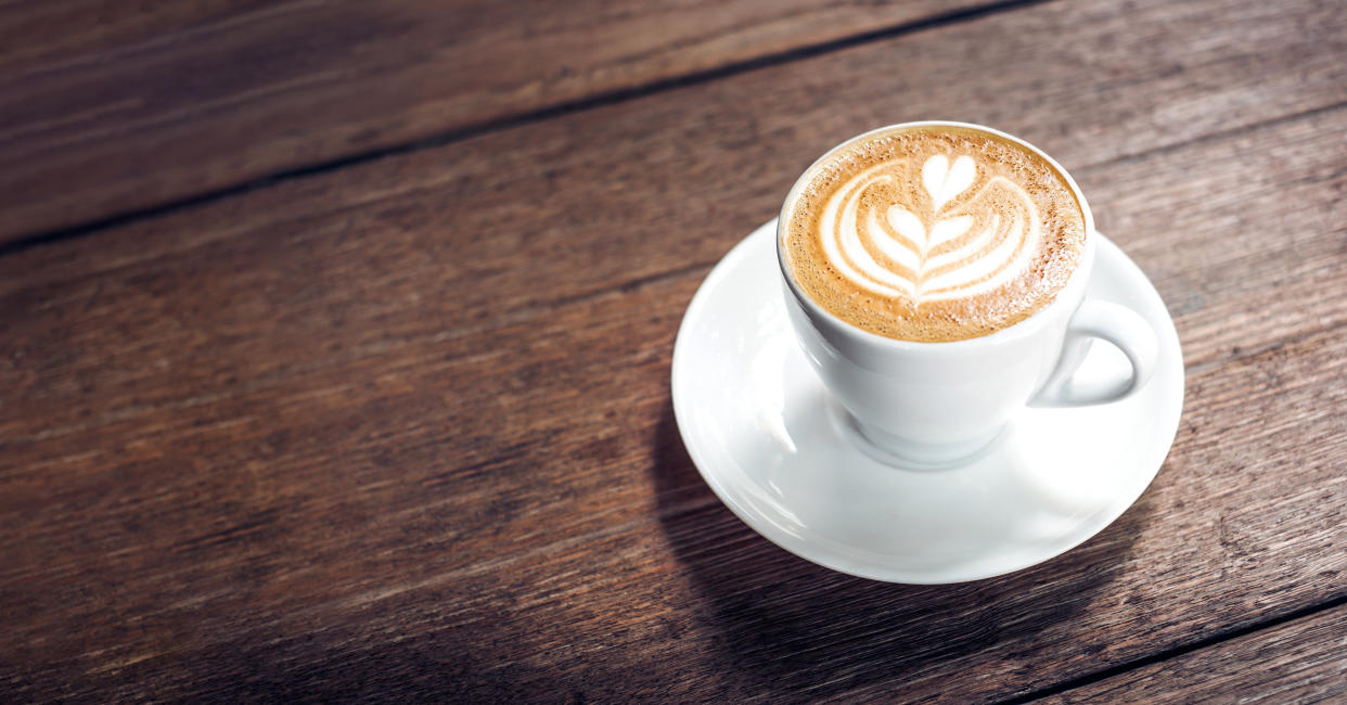 Close up hot cappuccino white coffee cup with heart shape latte art on dark brown old wood table at cafe,food and drink concept