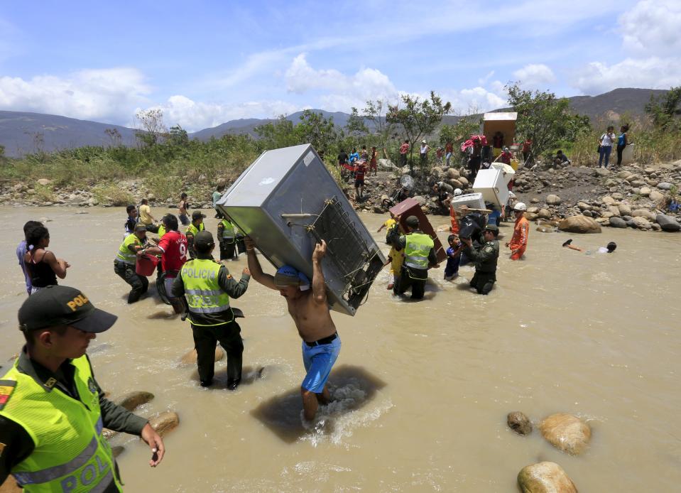 A man carries a refrigerator while crossing the Tachira river border with Venezuela into Colombia, near Villa del Rosario village