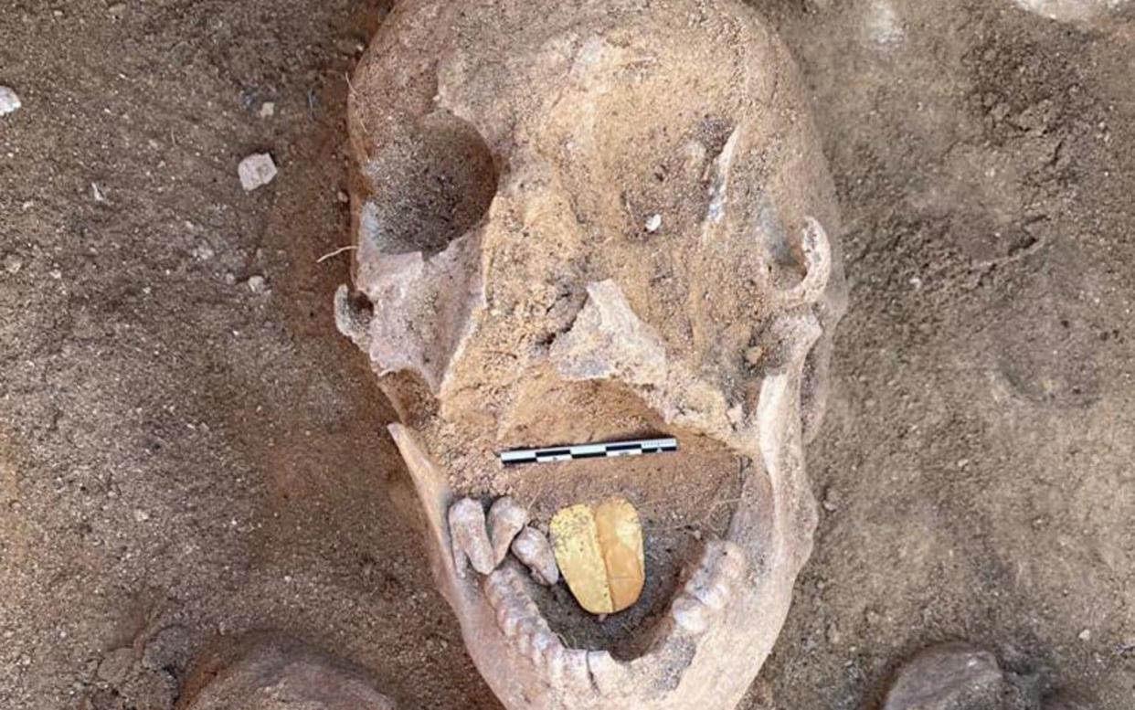 A decayed human skull with a clearly visible, golden-yellow amulet in its mouth - MINISTRY OF TOURISM AND ANTIQUTIES HANDOUT/EPA-EFE/Shutterstock