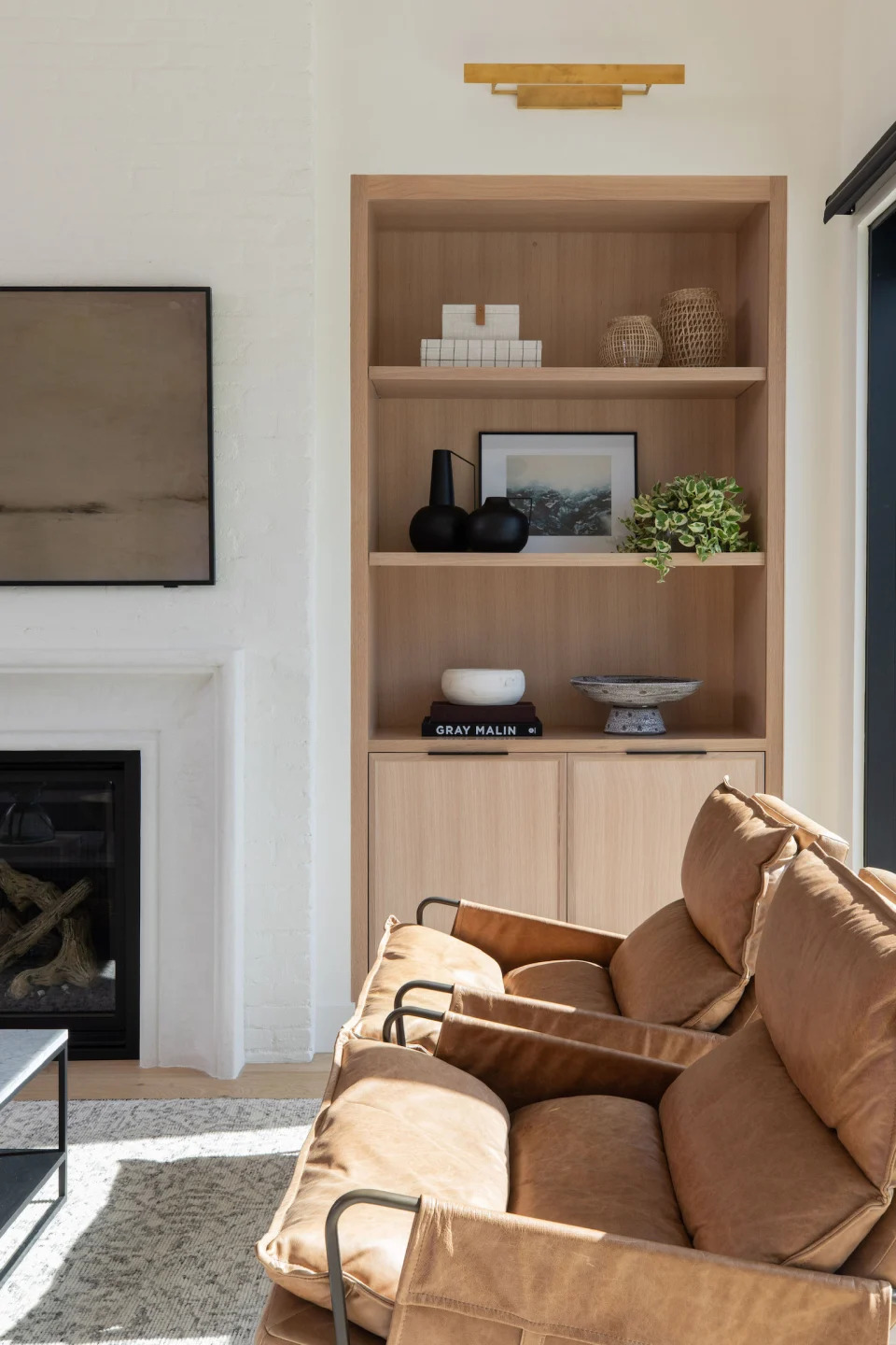 A set of shelves in a living room alcove decorated with books, a bowl, a plant, and other decor