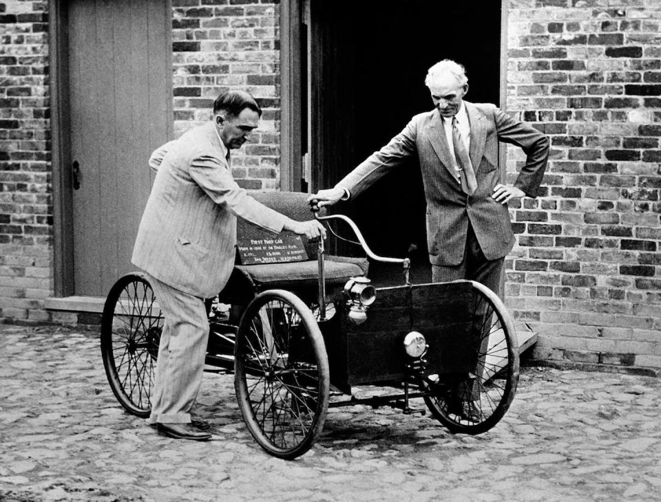 Henry Ford, right, stands with his first car built in 1892, seen here in 1936. (AP Photo)