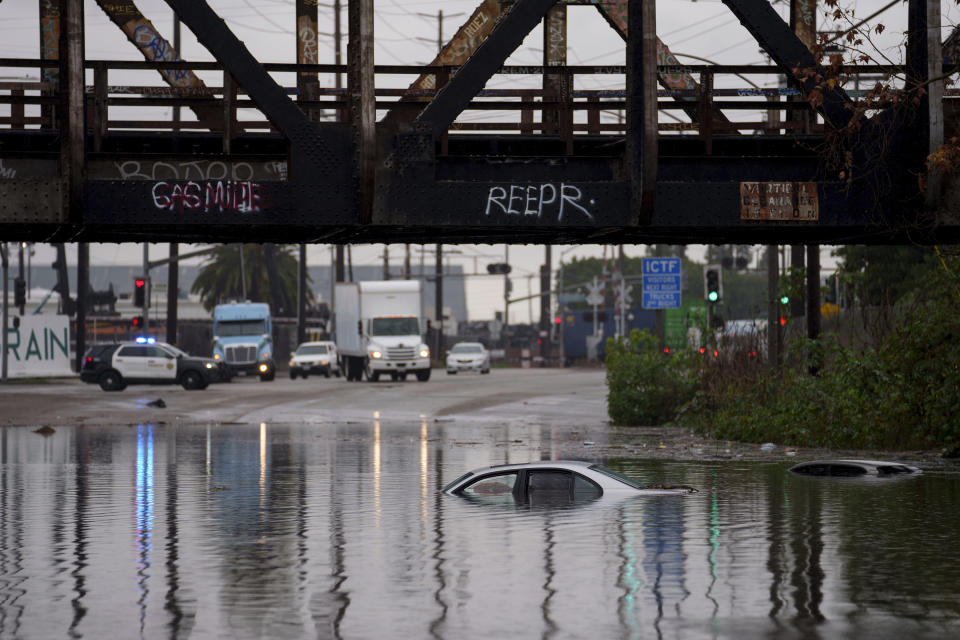 Cars are submerged on a flooded street under a railroad bridge Thursday, Feb. 1, 2024 in Long Beach, Calif. Heavy rain flooded roadways and much-needed snow piled up in the mountains on Thursday as the first of back-to-back atmospheric rivers pummeled California. (AP Photo/Eric Thayer)