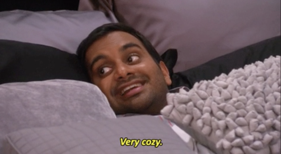 a man laying under pillows saying, "very cozy"