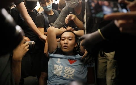 Protesters surround a man carrying a t-shirt baring the words "I love police" who protesters claimed was a police officer from mainland China - Credit: AP