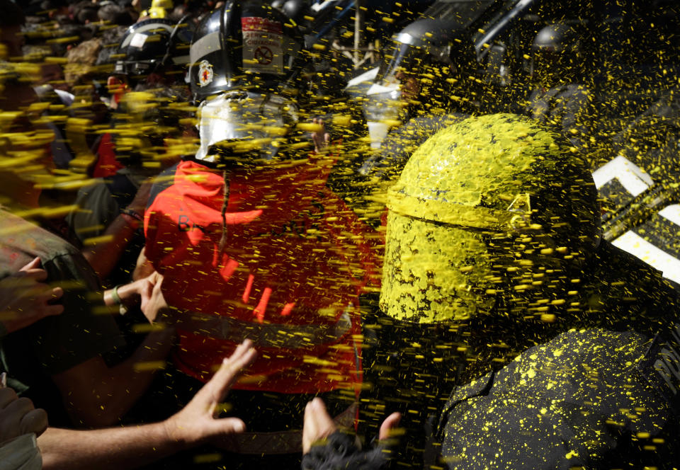 Pro independence demonstrators throw paint at Catalan police officers during clashes in Barcelona, Spain, on Saturday, Sept. 29, 2018. Catalan separatists clashed with police on Saturday in downtown Barcelona as tensions increase before the anniversary of the Spanish region's illegal referendum on secession that ended in violent raids by security forces. (AP Photo/Daniel Cole)