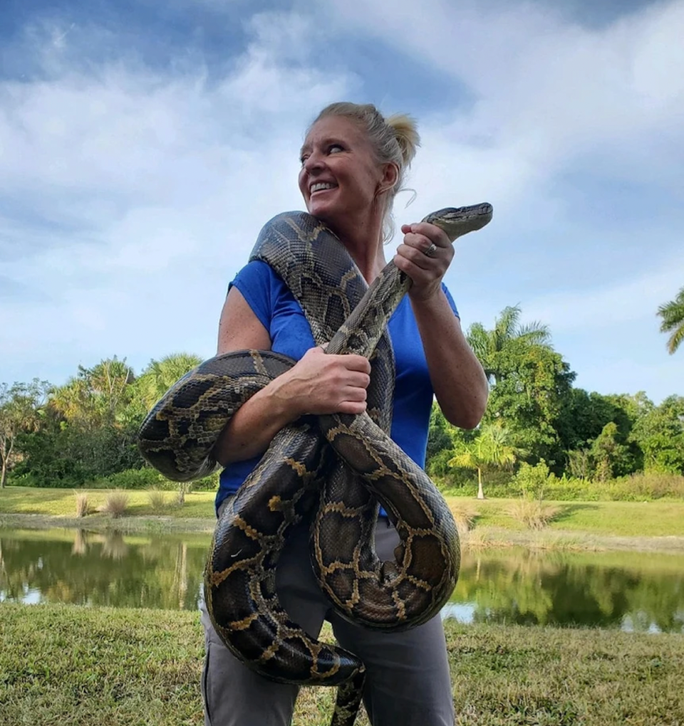 Amy Siewe poses with a 15-foot 2-inch long Burmese python she captured in July 2021 in Florida.