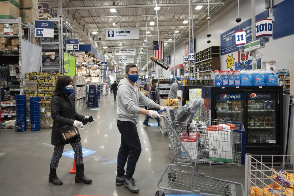 Lowe's customers wear gloves and masks as they shop, Friday, April 3, 2020, during the coronavirus pandemic in New York. (AP Photo/Mark Lennihan)