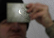 Un hombre observa un eclipse parcial de Sol a través de un filtro en Galyateto, a unos 100 kilómetros de Budapest, el 4 de enero del 2011. REUTERS/Bernadett Szabo