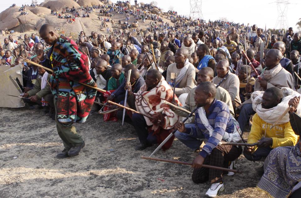 Striking miners gather together to sing, chant, march and dance with crudely made weapons and machetes at the Lonmin mine near Rustenburg, South Africa, Wednesday Aug. 15, 2012. Ongoing violence that started last Friday has seen 10 people killed, with no end to the strike in sight.(AP Photo/Denis Farrell)