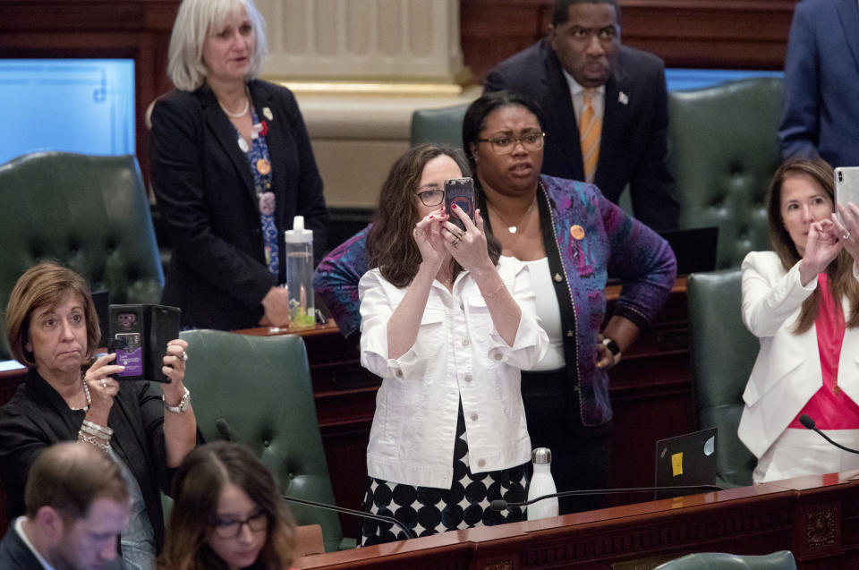Illinois state Reps. Rep. Sara Feigenholtz, left, D-Chicago, Kelly Cassidy, center, D-Chicago, and Jennifer Gong-Gershowitz, right, D-Glenview, film the vote on the Reproductive Health Act in the Illinois House chambers Tuesday, May 28, 2019, in Springfield, Ill. The House voted 64-50 on Rep. Cassidy's Reproductive Health Act, which would rescind prohibitions on some late-term abortions and restraints such as criminal penalties for doctors performing abortions. (Ted Schurter/The State Journal-Register via AP)