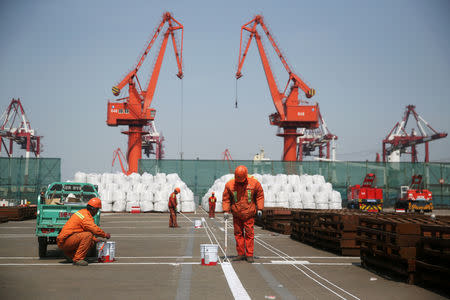 Workers paint the ground at a port in Qingdao, Shandong province, China April 9, 2018. REUTERS/Stringer/Files