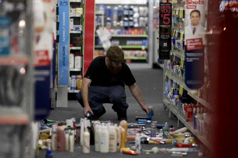A man picks up fallen goods at a CVS store after an earthquake on Friday, March 28, 2014, in La Mirada, Calif. A magnitude-5.1 earthquake was widely felt in the Los Angeles area and surrounding counties Friday evening, but authorities said there were no immediate reports of significant damages or injuries. (AP Photo/Jae C. Hong)