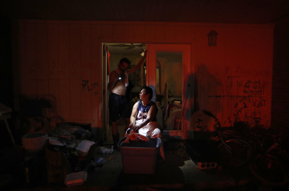 Tasha Hughes, bathes her daughter, Madison, 4, as Jeffrey Dumich holds a flashlight outside their room at the damaged American Quality Lodge where they continue to live without power in the aftermath of Hurricane Michael, in Panama City, Fla., Tuesday, Oct. 16, 2018. Simply getting through the day is a struggle at the low-rent motel where dozens of people are living in squalor amid destruction left by the hurricane. (AP Photo/David Goldman)