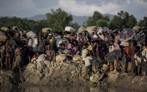 Rohingya refugees wait after crossing the Naf river from Myanmar into Bangladesh in Whaikhyang  - Credit: FRED DUFOUR/AFP/Getty Images