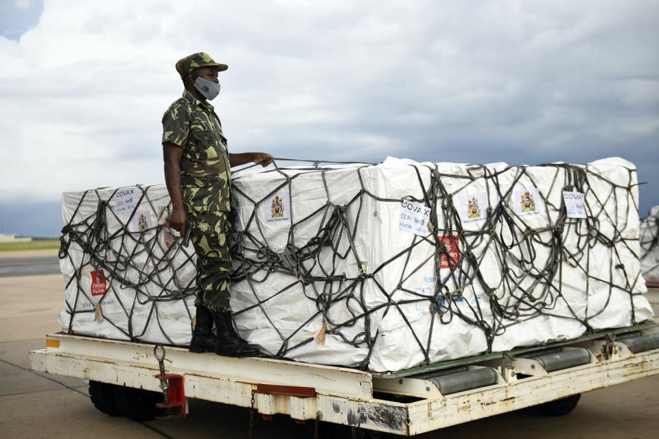 A policeman standing on a skip with crates of vaccine.