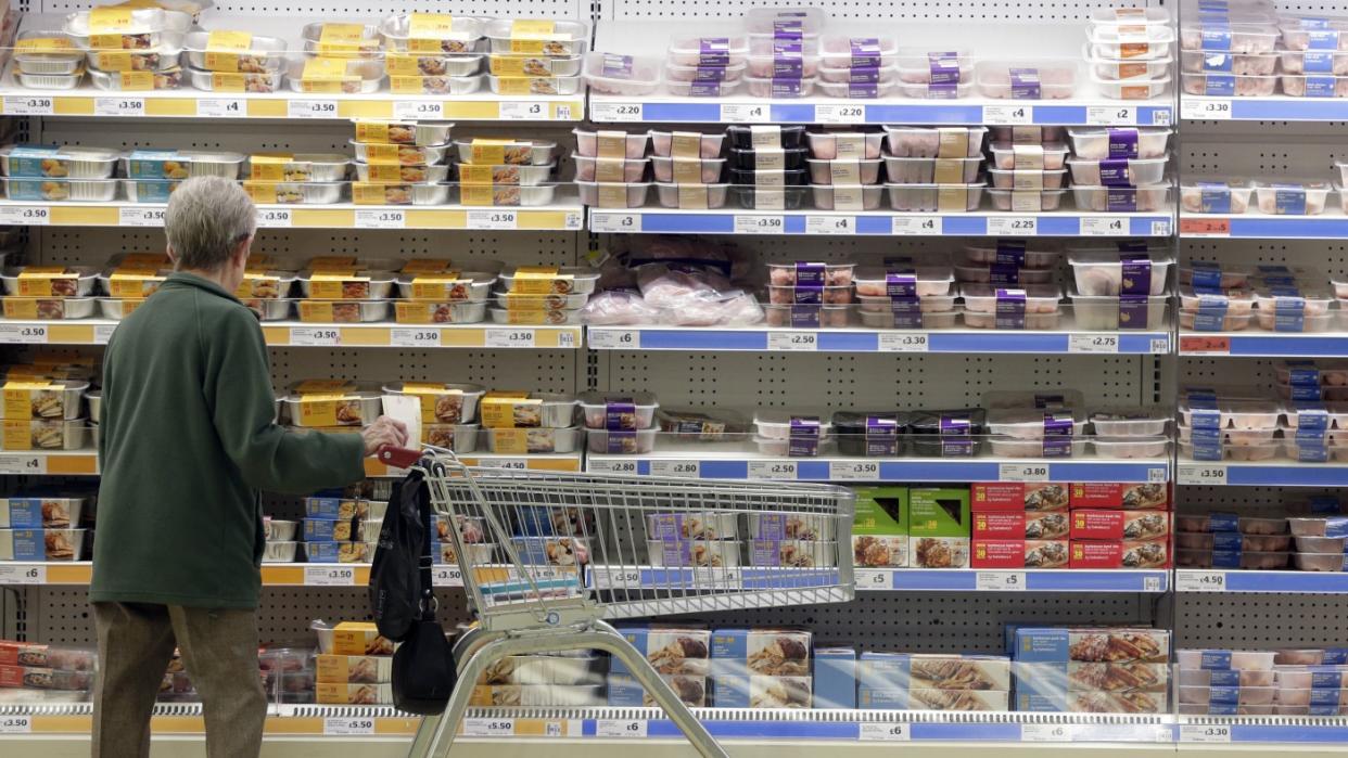  A supermarket shopper with a trolley looks at chilled cabinets of meat. 