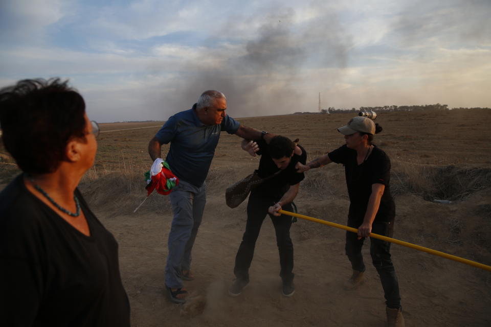 Two Israelis scuffle with a peace activist and take away a Palestinian flag on Israel Gaza border during a Palestinian protest at the fence, Friday, Oct. 5, 2018. (AP Photo/Ariel Schalit)