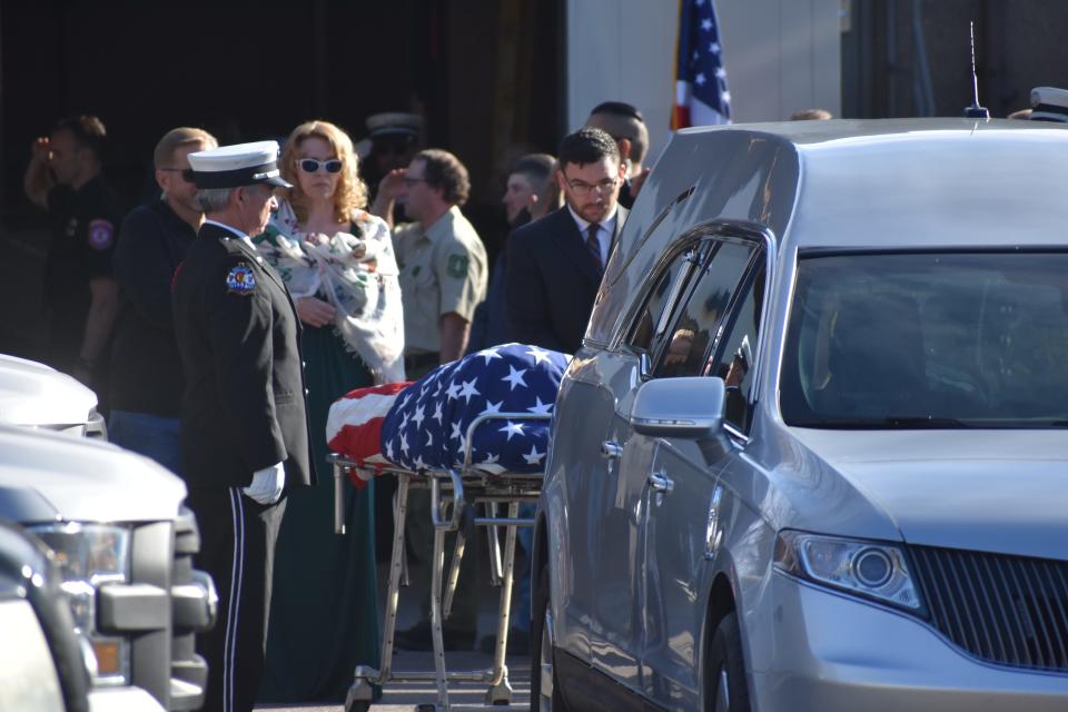 The American-flag draped body of fallen firefighter pilot Marc Thor Olson awaits being lifted into a hearse at the Larimer County Coroner's Office in Fort Collins, Colo, Monday, Nov. 22, 2021. A procession took the body from Fort Collins to Fort Morgan.