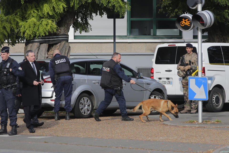 Police officers with a sniper dog arrive at the Gambetta high school during a bomb alert Monday, Oct. 16, 2023 in Arras, northern France. French authorities say the high school where a teacher was fatally stabbed in an attack last week has been evacuated over a bomb alert, as France's President cut short travel plans abroad to host a security meeting Monday.(AP Photo/Michel Spingler)