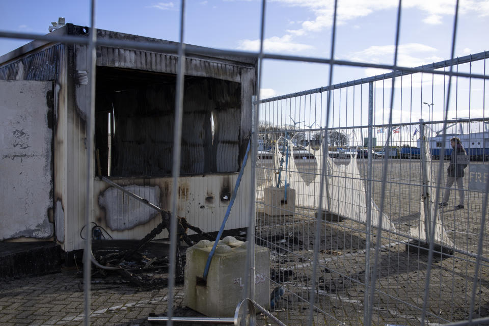 FILE - In this Jan. 24, 2021, file photo, a person walks past a burned-out coronavirus testing facility in the fishing village of Urk in the Netherlands after it was set on fire the night before by rioting youths protesting on the first night of a nationwide curfew. A new report by the Geneva-based Insecurity Insight and the University of California, Berkeley’s Human Rights Center identified hundreds of attacks linked to fear or frustration around the coronavirus against health care workers and facilities in the past year. (AP Photo/Peter Dejong, File)