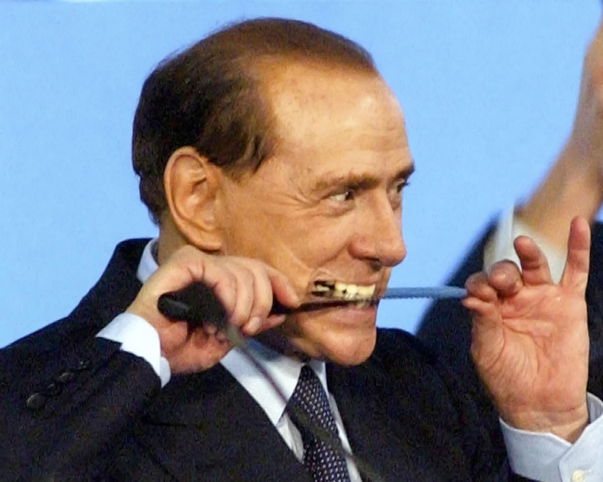 FILE - Italian Premier Silvio Berlusconi plays the pirate with a knife before cutting a cake at the "No Tax Day" meeting organized by Forza Italia (Go Italy) party in Mestre, Italy, Saturday, Dec. 11, 2004. Italy’s former premier Silvio Berlusconi is making his return to Italy's parliament, winning a seat in the Senate nearly a decade after being banned from public office over a tax fraud conviction (AP Photo/Antonio Calanni, File)
