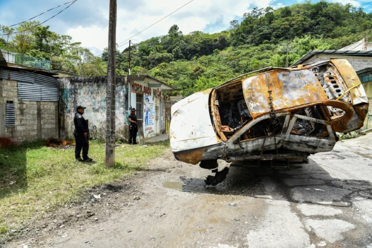 Unos oficiales de policía observan unos vehículos calcinados presuntamente por grupos armados en Tila, en el estado mexicano de Chiapas, el 12 de junio de 2024 (Isaac Guzmán)