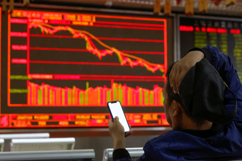 FILE PHOTO: An investor sits in front of displays showing stock information at a brokerage office in Beijing, China October 11, 2018. REUTERS/Thomas Peter