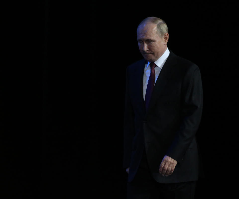 Russian President Putin, his head down, biting his lower lip, steps forward.