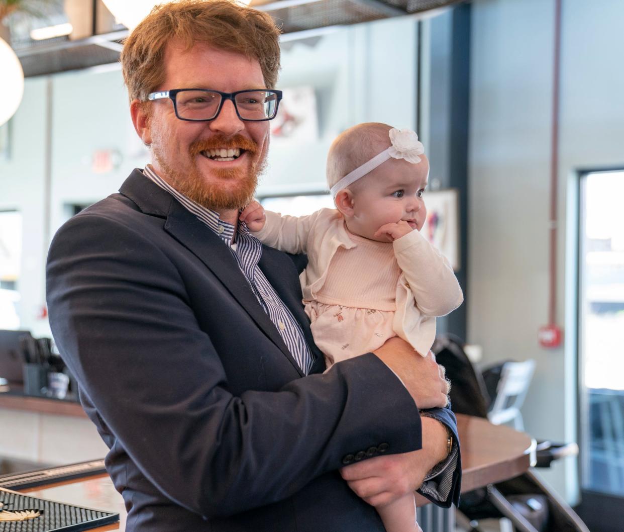 Democratic state Rep. Joey Andrews, of the 38th House District, is all smiles as he holds his 7-month-old daughter Violet before Michigan Gov. Gretchen Whitmer delivers her "What's Next" Address that outlines her legislative priorities for the fall at the Lansing Shuffle in Lansing Wednesday, Aug. 30, 2023.