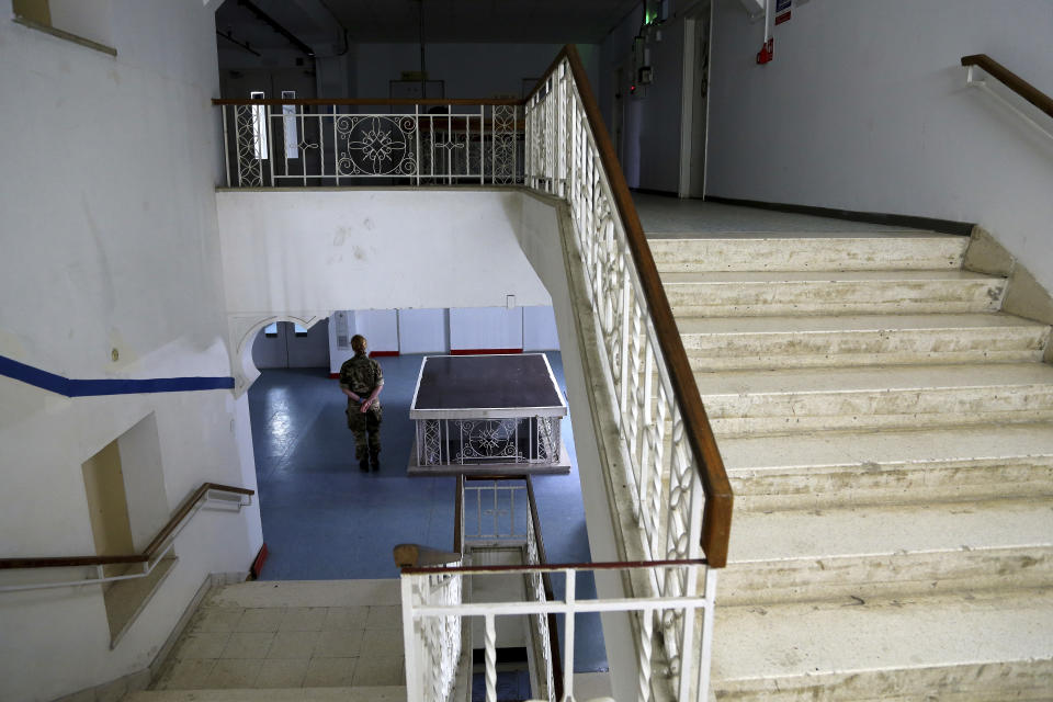 In this Friday, April 19, 2019, photo, a U.N. peacekeeper stands in a lower level of the Ledra Palace hotel inside the U.N. buffer zone in the divided capital Nicosia, Cyprus. This grand hotel still manages to hold onto a flicker of its old majesty despite the mortal shell craters and bullet holes scarring its sandstone facade. Amid war in the summer of 1974 that cleaved Cyprus along ethnic lines, United Nations peacekeepers took over the Ledra Palace Hotel and instantly turned it into an emblem of the east Mediterranean island nation's division. (AP Photo/Petros Karadjias)