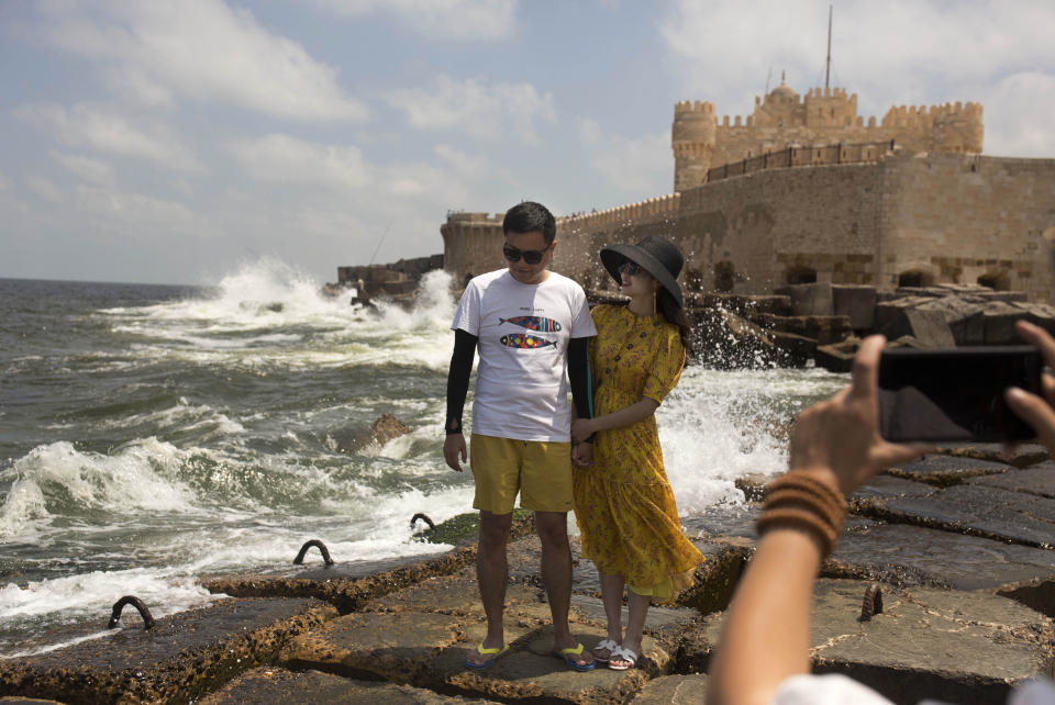 In this Aug. 8, 2019, photo, a couple poses for a portrait on cement blocks placed as reinforcement against rising water levels near the citadel in Alexandria, Egypt. Egypt’s coastal city of Alexandria, which has survived invasions, fires and earthquakes since it was founded by Alexander the Great more than 2,000 years ago, now faces a new menace from climate change. Rising sea levels threaten to inundate poorer neighborhoods and archaeological sites, prompting authorities to erect concrete barriers out at sea to hold back the surging waves. (AP Photo/Maya Alleruzzo)