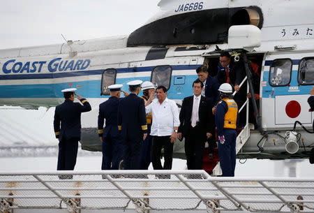 Philippine President Rodrigo Duterte (3rd R) is welcomed by Japan Coast Guard (JCG) officials as he arrives on the bridge of JCG patrol vessel Akitsushima by JCG helicopter for an inspection at the JCG base in Yokohama, south of Tokyo, Japan October 27, 2016. REUTERS/Issei Kato